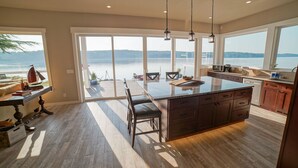 A spacious kitchen with a large island, wooden flooring, and a view of a lake.