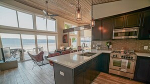 A modern kitchen with a large island, stainless steel appliances, and a view of the water.
