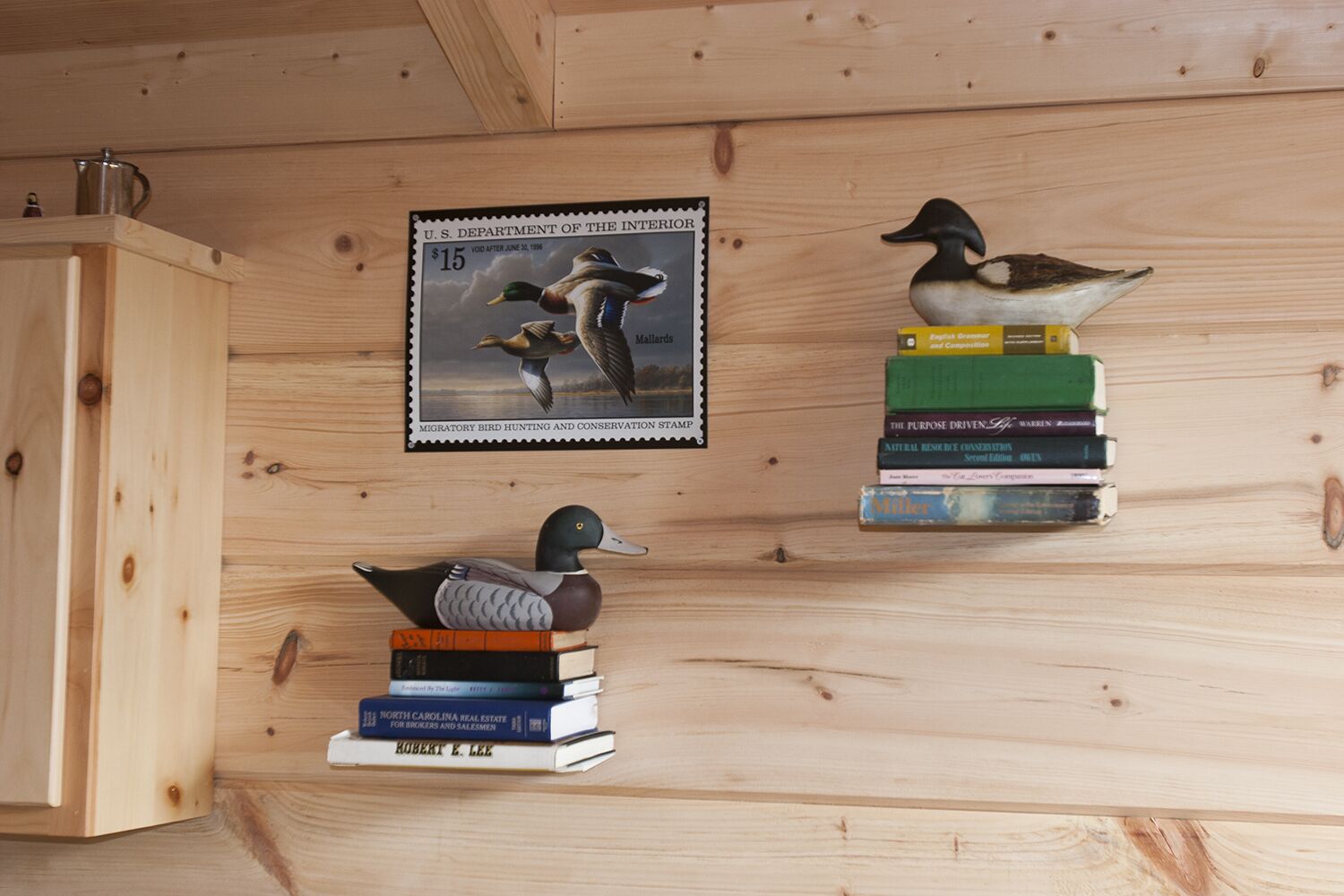 Un interior de madera con un sello en la pared, una figurita de pato y una pila de libros.