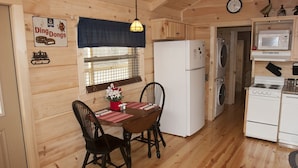 Un intérieur en bois comprenant une table à manger, des chaises, un réfrigérateur, un lave-linge, un four à micro-ondes et une cuisinière.