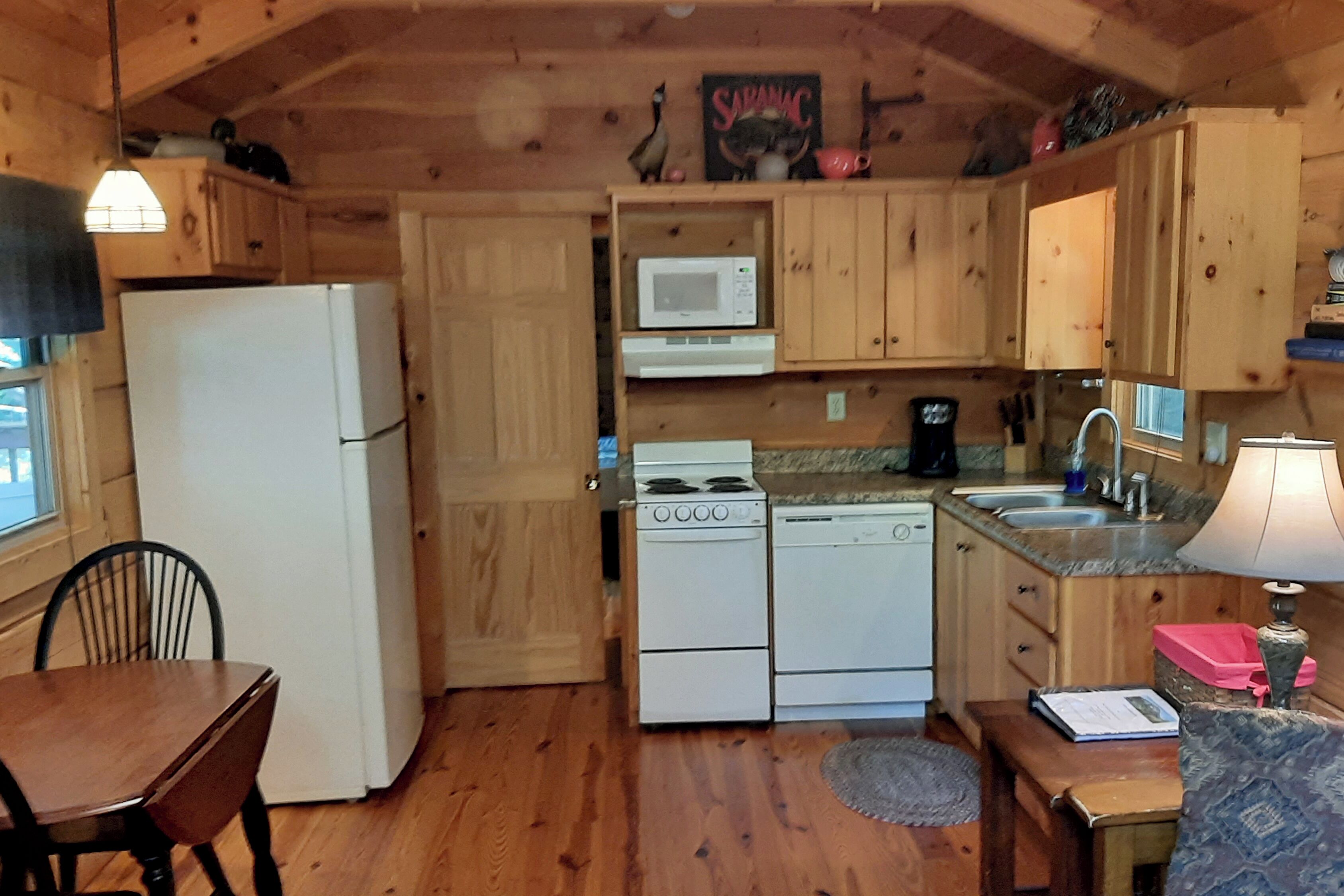 A wooden cabin kitchen with a refrigerator, stove, microwave, and sink.