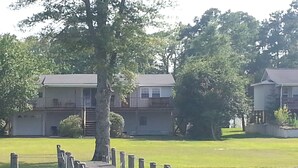 A wooden dock extending into a body of water, surrounded by lush greenery and residential buildings. - Relatively Secluded Location Yet Only 10 Minute Drive To Pubs And Restaurants. (Chocowinity)