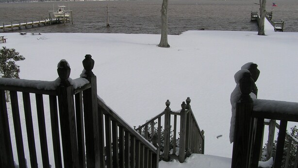 A snow-covered staircase leading to a dock by a lake with a view of a tree and a distant shoreline. - Relatively Secluded Location Yet Only 10 Minute Drive To Pubs And Restaurants. (Chocowinity)