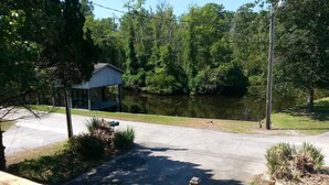 A residential area with a paved driveway, a wooden fence, and a pond. - Relatively Secluded Location Yet Only 10 Minute Drive To Pubs And Restaurants. (Chocowinity)