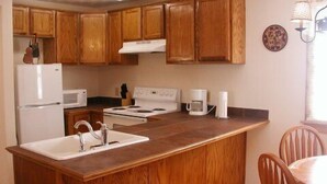A kitchen with wooden cabinets, a white refrigerator, a stove, a sink, and a coffee maker.