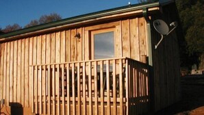 A wooden cabin with a balcony, a satellite dish, and a window.