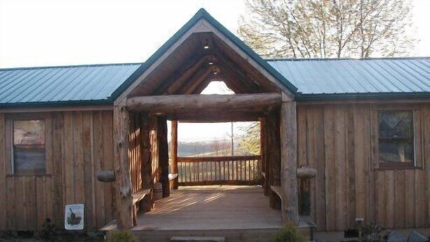 A wooden lodge with a porch and a metal roof.