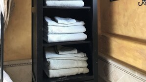 A black shelf with folded towels and two candles in a bathroom. - Private Guest Unit with backyard, Home away from home! (Santa Ana)