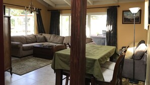 A living room with a sofa, a dining table, and a lamp. - Private Guest Unit with backyard, Home away from home! (Santa Ana)