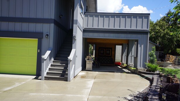 A modern two-story house with a green garage door, a wooden front door, and a concrete driveway. - Fun Guest Quarter With Bathroom Available For Rent Close To Downtown Bend. (Bend)