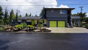 A modern two-story house with a garage, a well-maintained garden, and a clear sky. - Fun Guest Quarter With Bathroom Available For Rent Close To Downtown Bend. (Bend)