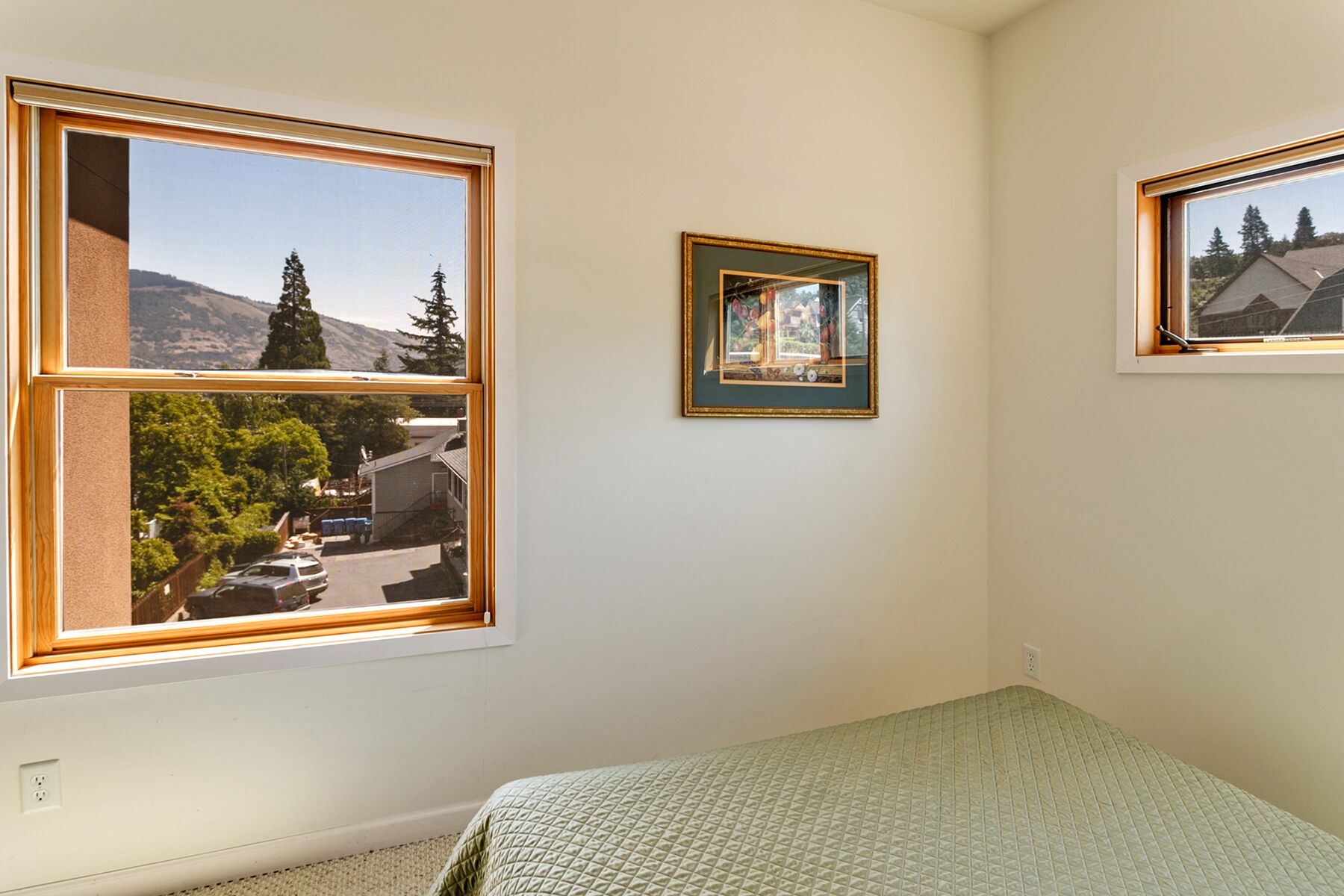 Quarto com uma cama, duas janelas e um quadro na parede.