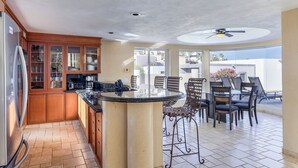 A kitchen with wooden cabinets, a refrigerator, and a dining area with a round table and chairs.