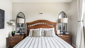 A neatly arranged bedroom with a wooden headboard, two bedside tables with lamps, a bed with striped bedding, and a small framed fish picture on the wall. - NASH Lakehouse 5 bedroom 30 mins to downtown  (Mount Juliet)