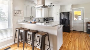 A modern kitchen with a central island, bar stools, a refrigerator, and a microwave. - NASH Lakehouse 5 bedroom 30 mins to downtown  (Mount Juliet)