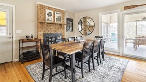 A dining area with a wooden table and chairs, a brick fireplace, and a large mirror. - NASH Lakehouse 5 bedroom 30 mins to downtown  (Mount Juliet)