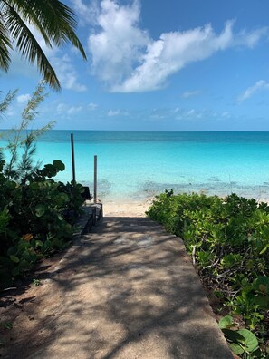 A concrete pathway leading to a beach with clear turquoise water and a clear sky. - Tequila Sunset-Only Beach Front Home in Oleander Gardens (Gregory Town)