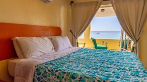 Habitación de hotel con cama, vistas al mar y un balcón con una silla.