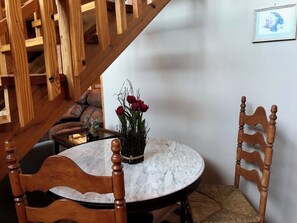A dining area with a round marble table, wooden chairs, a vase with red flowers, and a staircase in the background. - Cabin with beautiful view, on 'Peaceful Side of the Smokies' (Townsend)