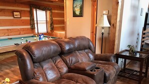 Una sala de estar acogedora con un sillón de cuero, una mesa de billar y una lámpara.