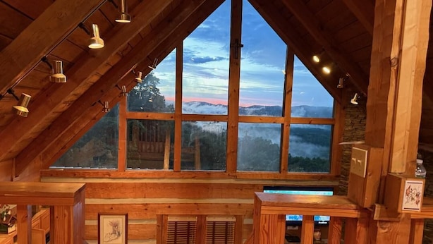 Un interior de madera con un ventanal grande que da a un paisaje montañoso.