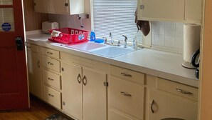 Una cocina compacta con fregadero, armarios y un cubo de basura.
