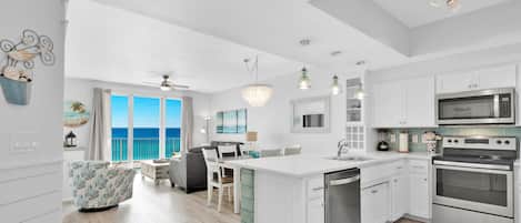 A modern kitchen with white cabinetry, stainless steel appliances, and a large island.