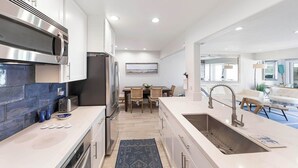 A modern kitchen with white cabinets, a stainless steel range hood, a built-in oven, and a large island with a sink. - Spectacular Oceanfront  - the Best Views in Dana Point !!!!! (Dana Point)