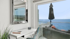 A balcony with a view of the sea, a wicker sofa with cushions, a white desk with a book and a glass, and a large mirror on the wall. - Spectacular Oceanfront  - the Best Views in Dana Point !!!!! (Dana Point)
