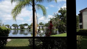Vista de un lago con una casa flotante, rodeada de árboles y una valla.