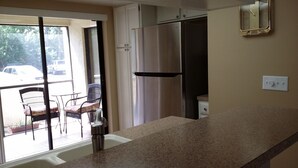 Una cocina con un refrigerador de acero inoxidable, un fregadero y una ventana con vista a un estacionamiento.