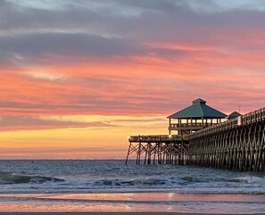 A wooden pier extending into the sea with a gazebo structure at the end.