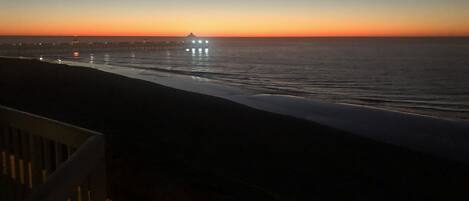 A coastal sunset view with a pier in the distance.