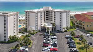 A hotel with a central courtyard, multiple parking spaces, and a view of the beach and ocean.
