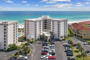 Ein Hotel mit Innenhof, mehreren Parkplätzen und Blick auf Strand und Meer.