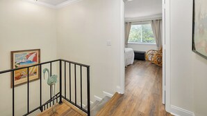 A hallway with a wooden floor, a black railing, and a painting on the wall. - YOUR ISLAND DESTINATION IS WAITING! (Saint Simons Island)