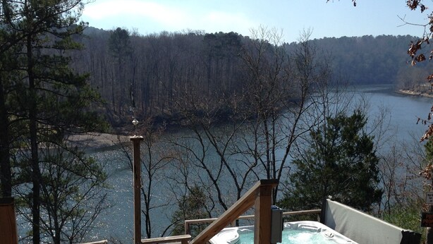 A wooden deck leading to a hot tub with a lake view. - Lake Cabin on the Bluff (Hot Springs)
