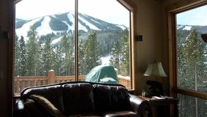 A room with a large window offering a view of a snowy mountain landscape.