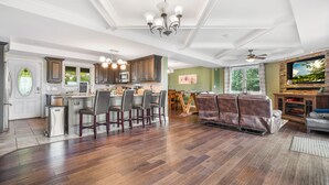 A spacious kitchen with a dining area, a fireplace, and a large window.