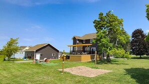 A residential area with a house featuring a wooden deck and a volleyball net in the yard.