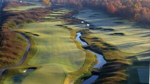 A golf course with multiple holes, water hazards, and a surrounding wooded area.