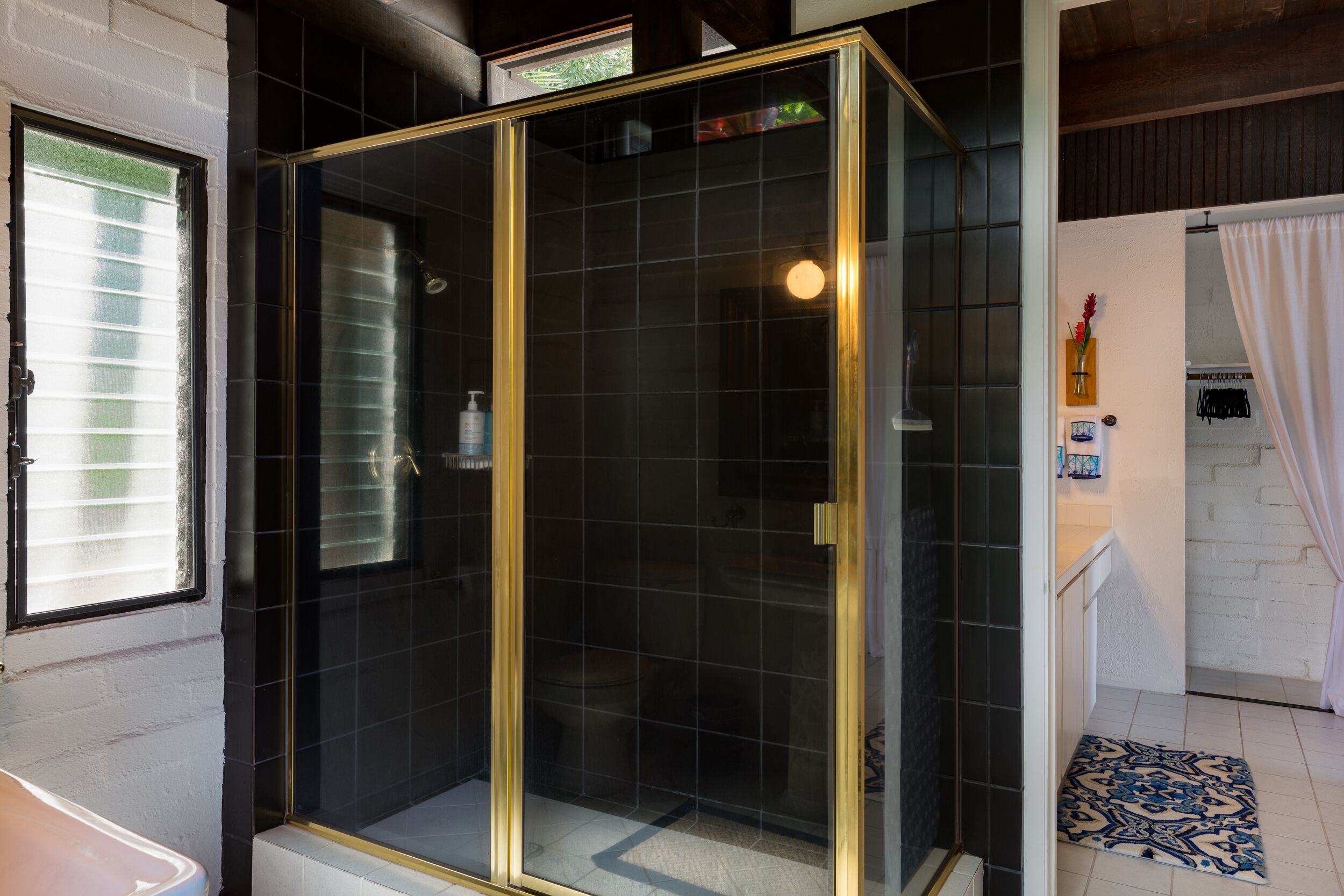 A modern bathroom with a glass-enclosed shower, a white sink, and a tiled floor.