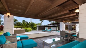 An outdoor patio area with wicker furniture, a glass table, and a pool in the background. - Private Oceanview Oasis w/Pool, Spacious Lanai, & Stunning Sunsets: Ono Oasis (Kailua Kona)