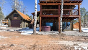 Una cabaña de dos pisos con fachada de madera, un jacuzzi visible y un letrero que indica que es el Twin Aspen Lodge.