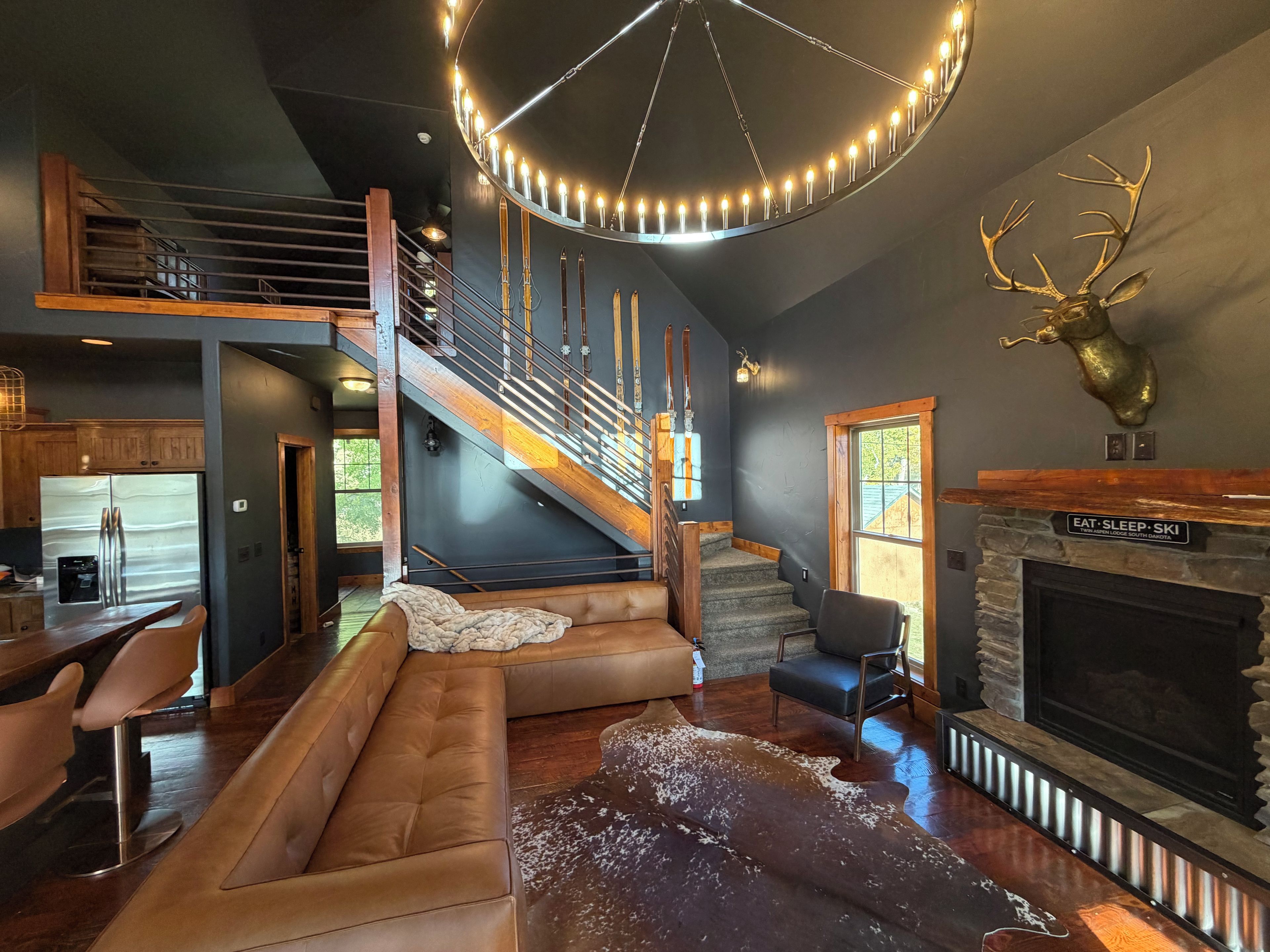 A modern interior with a staircase, leather seating, a fireplace, and a mounted deer head.