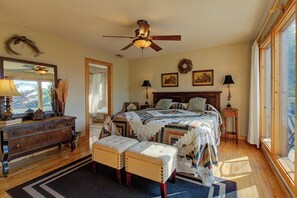 A bedroom with a large bed, a ceiling fan, a dresser, a bench, and a window with curtains. - Tanasi Lodge | Wake Up to Top-of-the-World Views | 10BR | Sleeps 30 (Sevier County)
