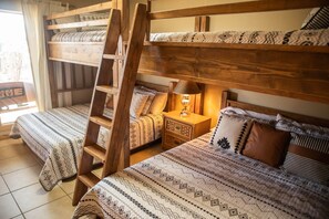 Habitación con literas, mesitas de noche y ropa de cama estampada.