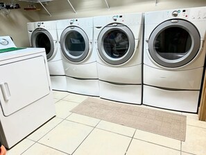 A laundry room with three stacked front-loading washing machines and a single side-by-side dryer. - Tanasi Lodge | Wake Up to Top-of-the-World Views | 10BR | Sleeps 30 (Sevier County)