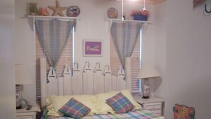 Ein Schlafzimmer mit einem Bett, zwei Nachttischen, einer Kommode und einer Wand mit Dekoration.