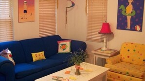 Ein Wohnzimmer mit blauem Sofa, gelbem Sessel und weißem Couchtisch.